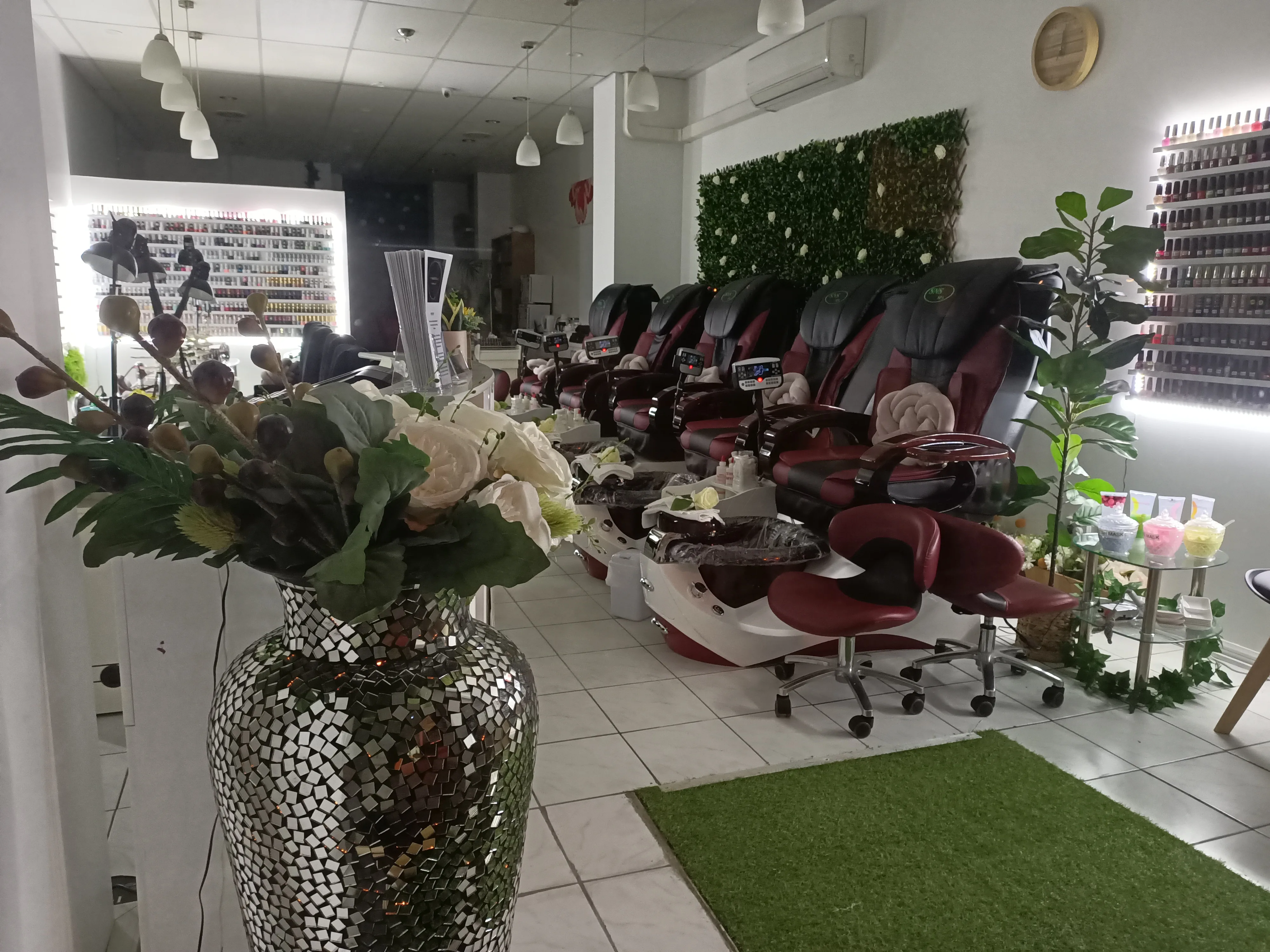 The pedicure row at Sun Nails & Beauty — five burgundy spa thrones receding down the room, white roses and ivy in the foreground