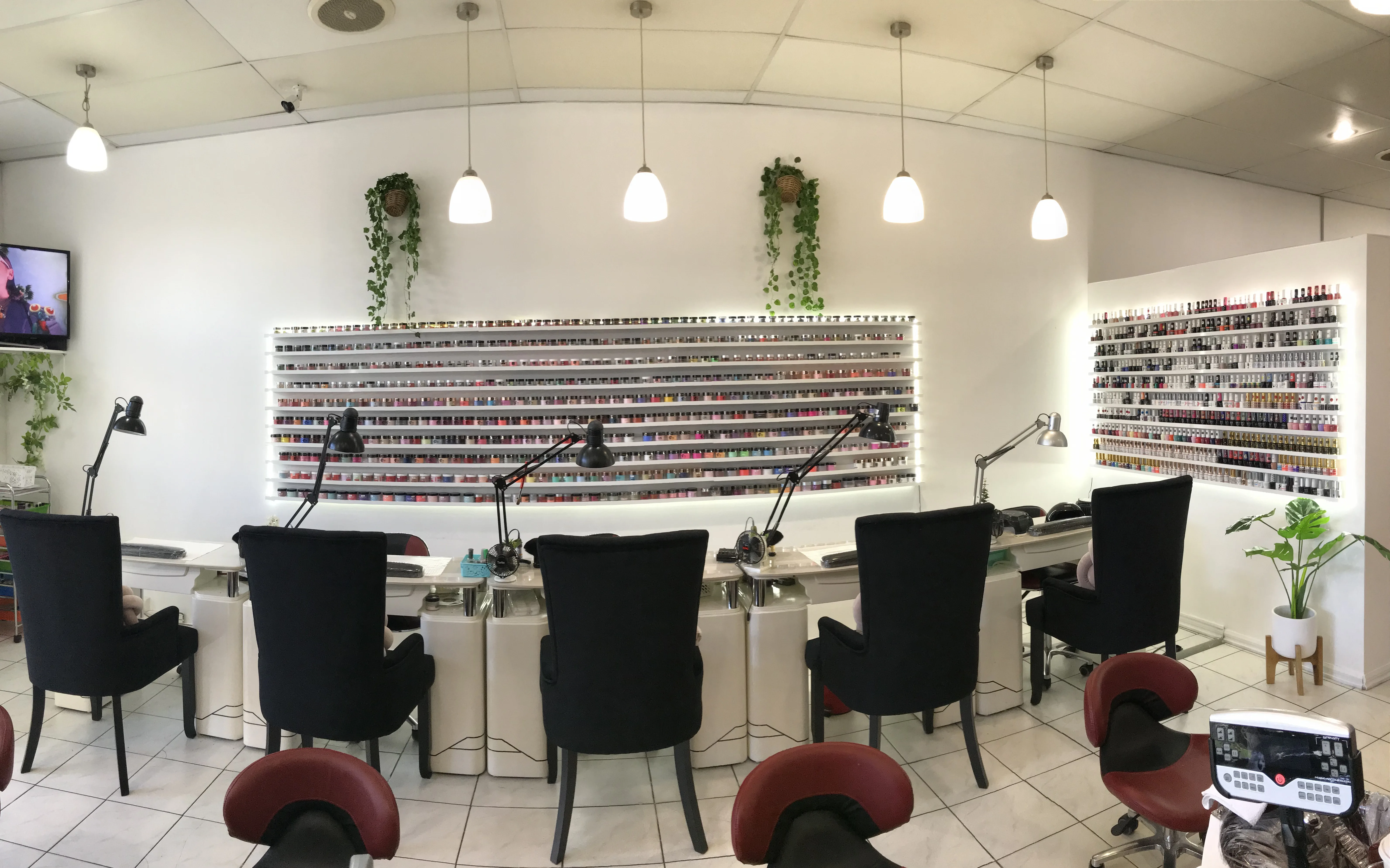 Sun Nails & Beauty's curved back-lit polish wall — hundreds of colour bottles on illuminated tiered shelves filling the manicure room