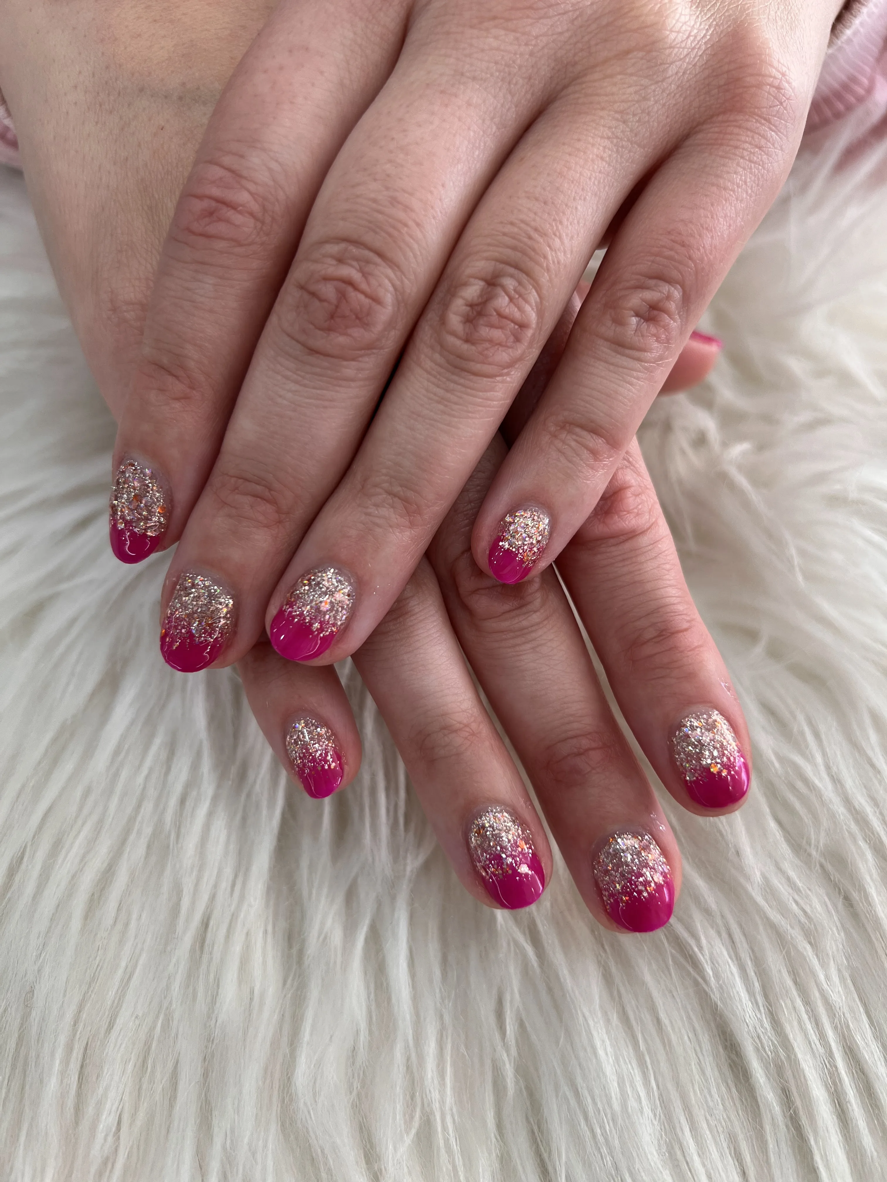 Short round nails in a silver-glitter-to-magenta ombré, glitter dense at the cuticle