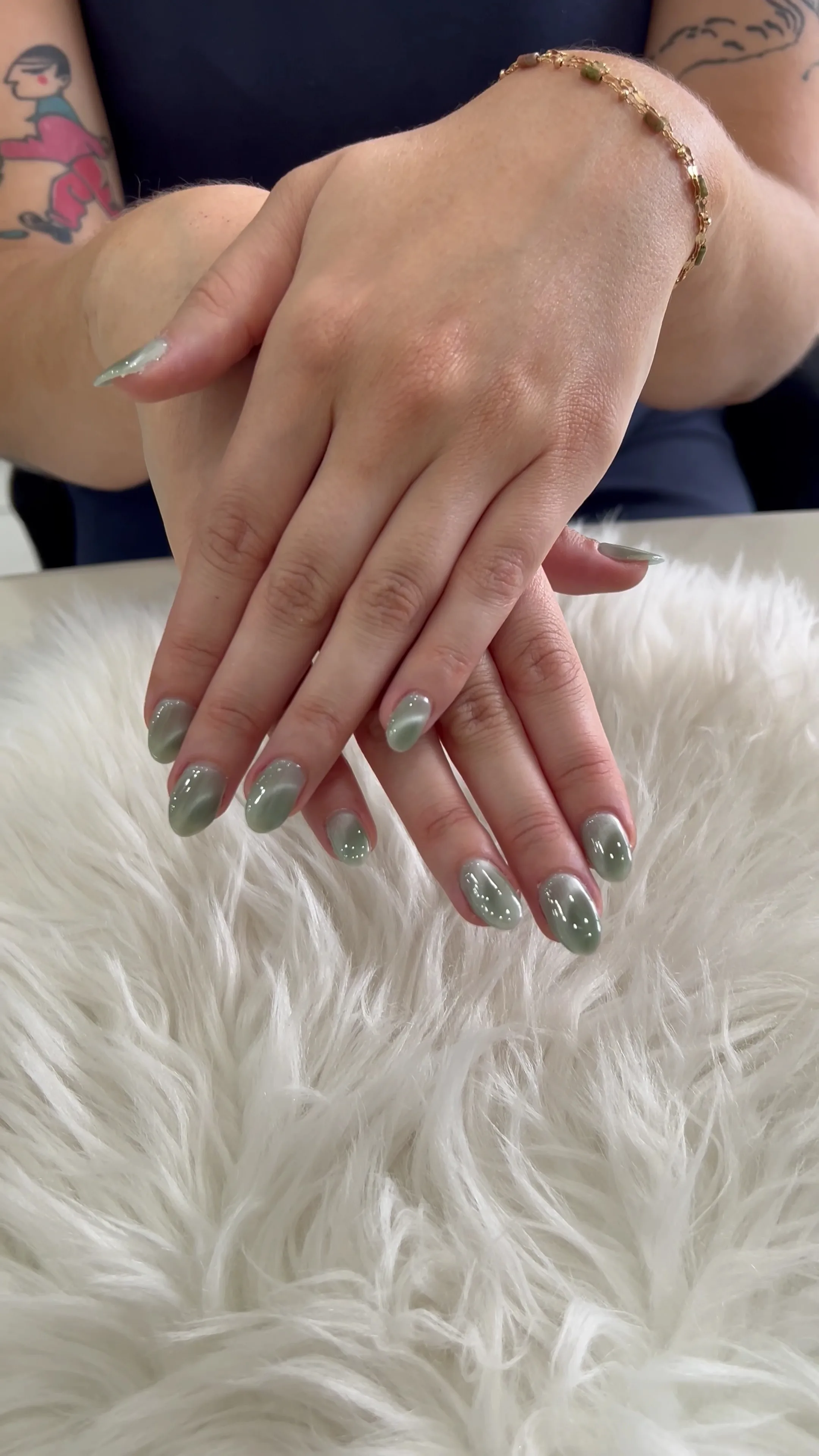 Medium almond nails in sage-green cat-eye with fine white dot detailing